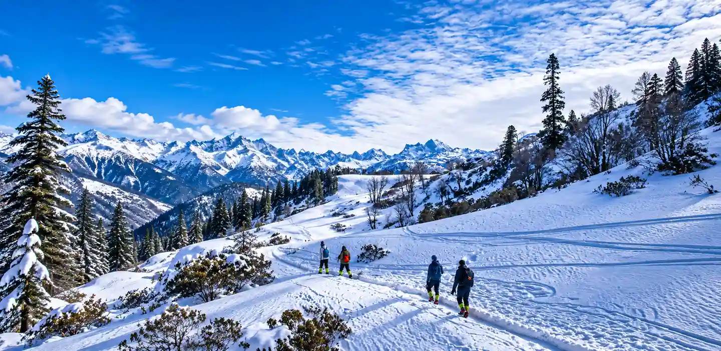 Manali tour package from Kerala with trekkers walking across snowy slopes toward snow-capped mountains.